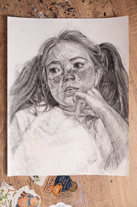 Pencil drawing of a young girl on a wooden surface with stickers.