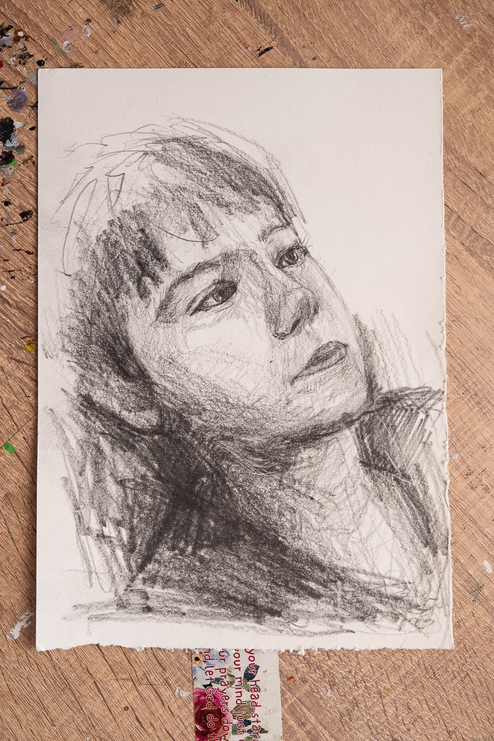 Pencil sketch of a woman's face on a textured wooden surface