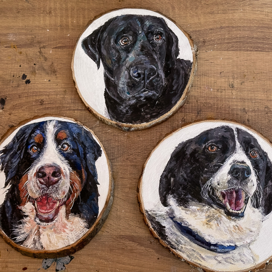 Three dog portraits on wooden slices with a brown background